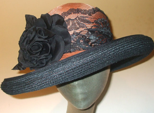 The brim is lined with black Milano straw; the crown is surrounded in French lace with a large flower.