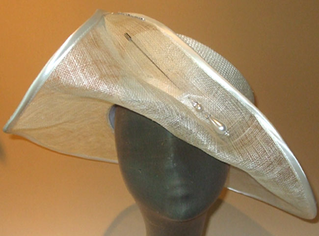 A hat for a new look, with see-through sinamay brim, sporting a pearl hatpin.