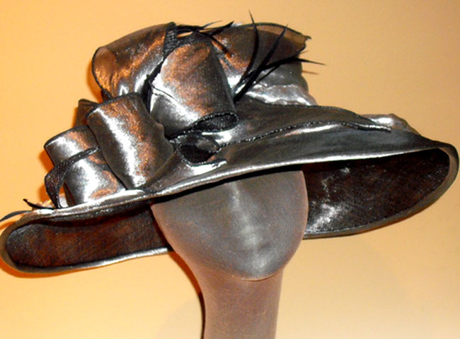 This sophisticated sinamay hat is covered metallic organza with a big multi-looped bow.
